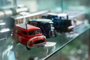 A vintage miniature red van toy in a glass display cabinet
