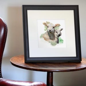 A photograph of two white sheep in a black frame by Lee Atherton Photography, displayed on a wooden table in a sitting room setting