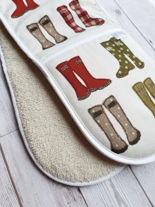 A pair of oven gloves with a pattern design of wellington boots of various colours