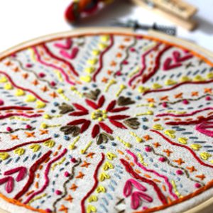 Close up of a circular embroidery kit showing a brightly coloured embroidered design
